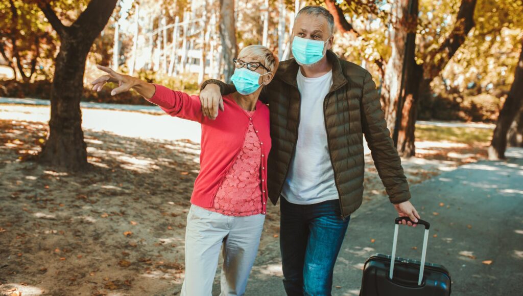 Older couple wearing face masks, traveling in fall